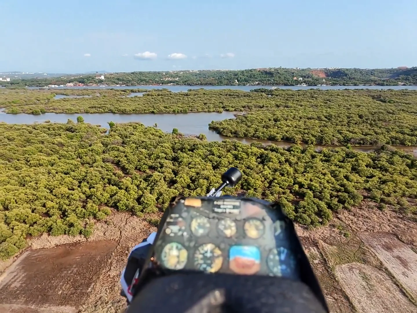 A single frame off the live link in flight: the aircraft’s instrument panel sharp against the coastline below